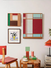Red House wall art hung above a stool and desk in a cozy room setting, paired with complementary decor pieces, emphasizing its vibrant red and turquoise palette.
