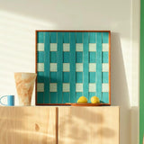 Square textured soft cotton cord wall decor placed above a light wood cabinet, highlighting the vibrant coastal teal tones and organic materials.