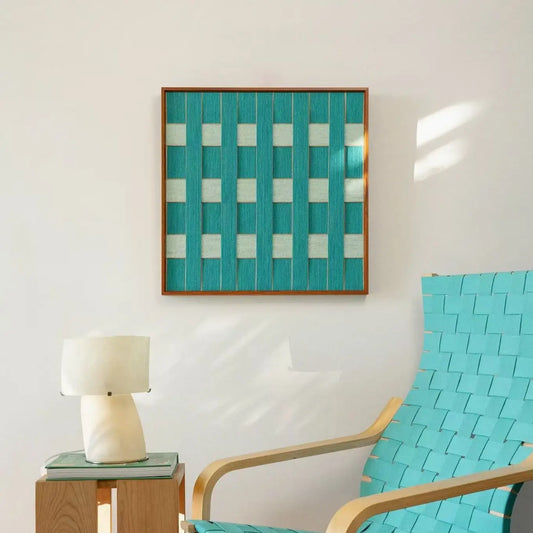 Hand-woven wool wall art with a teal and cream checkerboard weave displayed above a modern lounge chair and stone lamp.