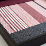 Angled close-up of the Rosy Pulse fiber art showing the dense soft cotton cord texture and sleek black metal frame finish.