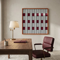 Large square Ruby Lattice fiber wall art featuring woven grey and burgundy red patterns, hanging in a sophisticated home office above a dark wooden desk and leather chair.