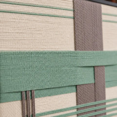 Detailed macro shot of the Sage Crossing hand-woven wool tapestry highlighting thick sage green and grey intersecting yarn textures.