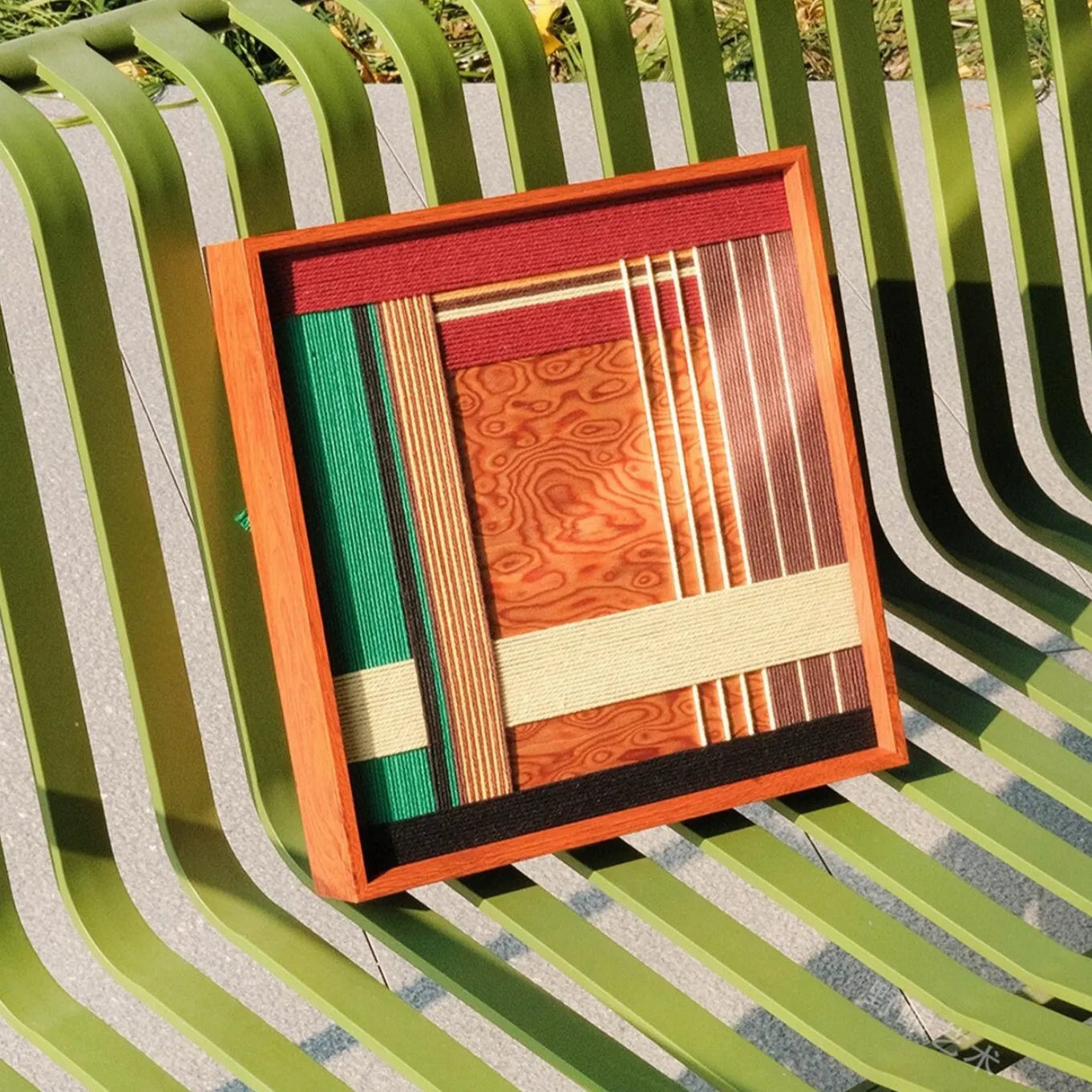 Saint Christmas yarn wall art displayed on a patterned cushion bench, focusing on its even stripe alignment and natural wood frame contrast
