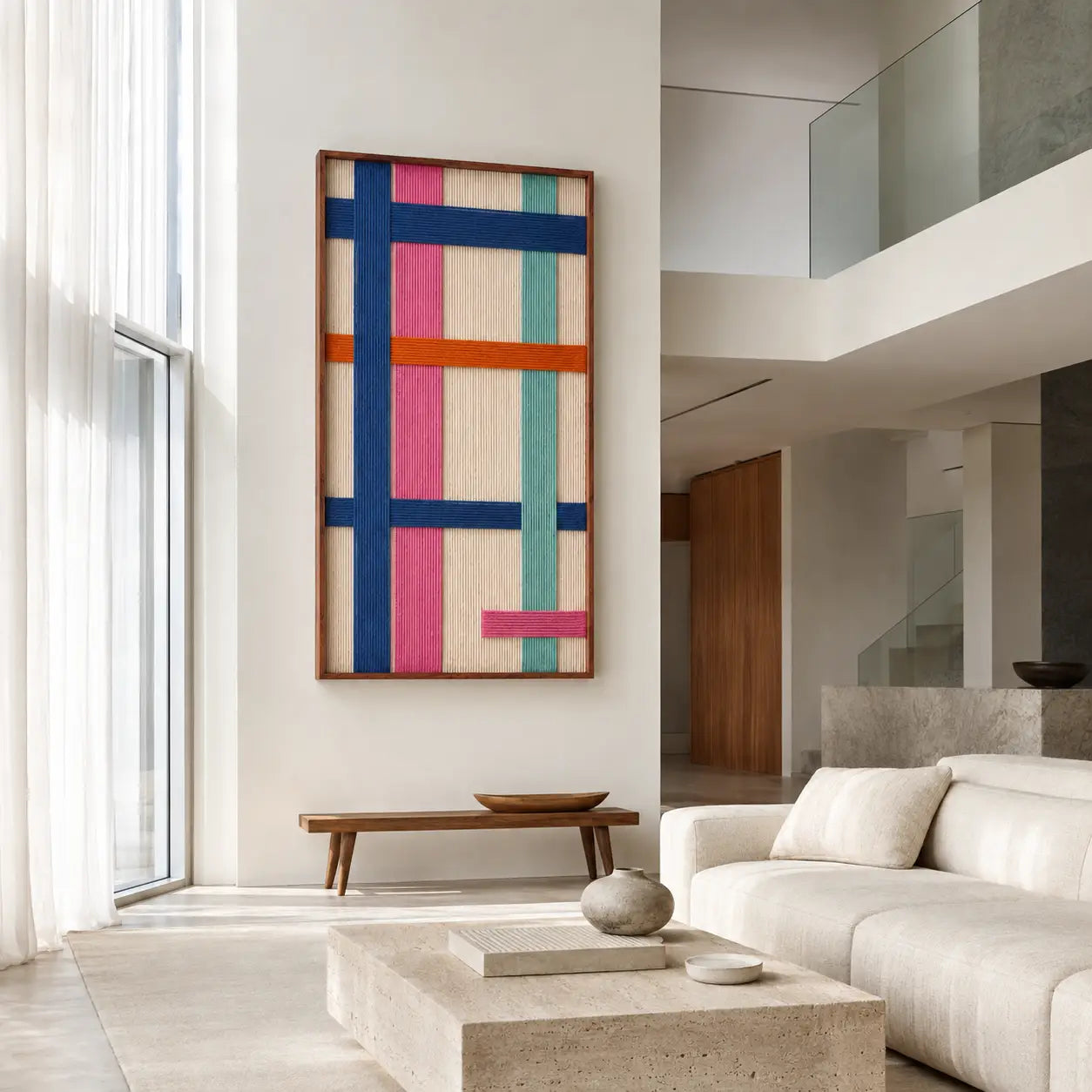 Modern living room interior featuring a large vertical hand-woven wool tapestry with blue, orange, and pink geometric patterns hanging on a neutral wall.