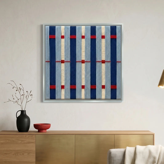 Hand-woven wool wall art with navy blue and red nautical stripes hanging above a modern gold and wood sideboard.