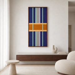 Cozy living room decor displaying the geometric framed wool tapestry hanging above a low wooden media console in a bright space.