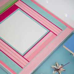 Angled close-up of Secret Crush yarn mirror art showing looped wool texture and crisp transitions between pink, green, and ivory panels.
