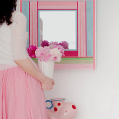 Secret Crush mirror art in the hands of someone hanging it, highlighting its lightweight frame and easy-install design.
