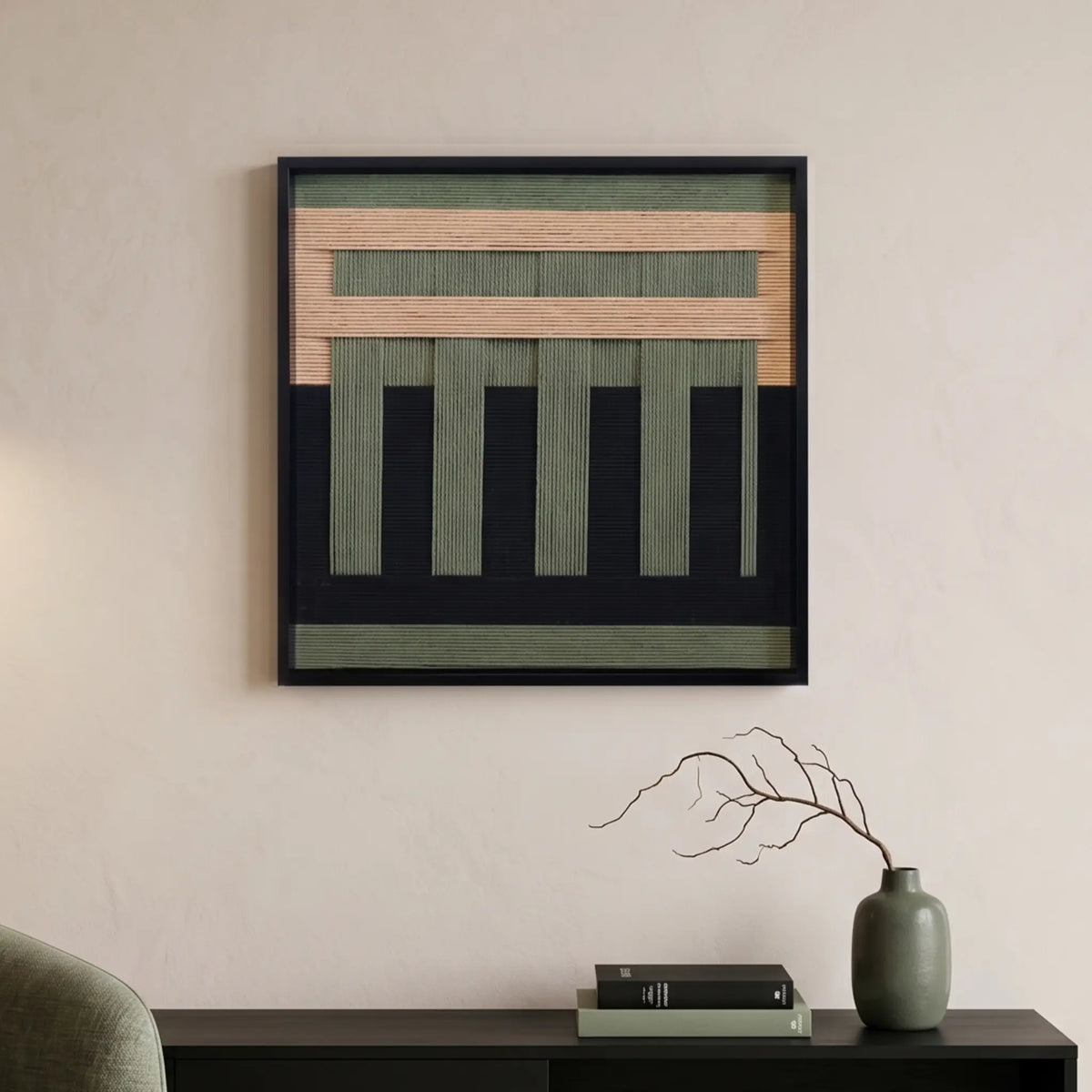 soft cotton cord wall art with forest green and tan geometric patterns hanging above a black console table with minimalist decor.