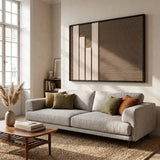 Elegant Silent Stelae textile art hanging above a plush beige sofa in a sunlit room, showcasing the contrast of cream and dark brown wool.