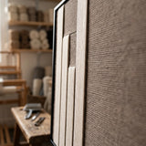 Detailed macro view of the Silent Stelae hand-woven wool tapestry featuring raised cream vertical panels against a textured dark brown background.
