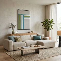 Modern hand-woven wool tapestry hanging in a contemporary living room above a cream sectional sofa and neutral area rug.