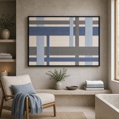 Framed hand-woven wool tapestry styled in a cozy lounge nook positioned above a built-in shelf next to an armchair.