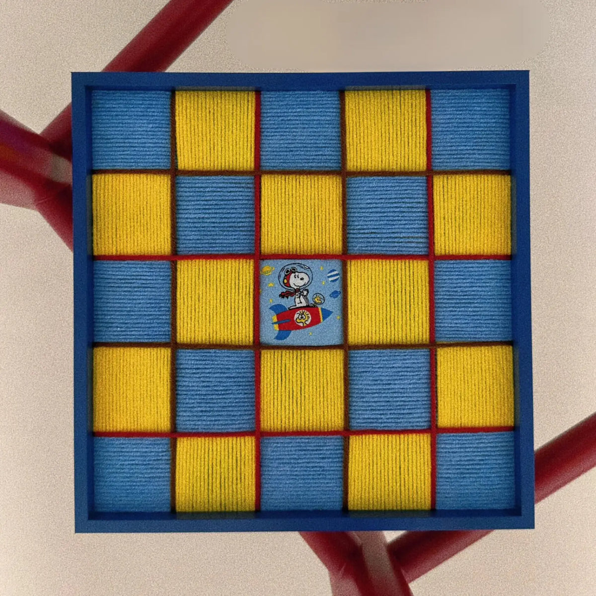 Close-up front view of the textured fiber wall art showing the yellow and blue textured checkerboard pattern and a central Snoopy space patch.