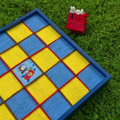 Whimsical outdoor display of the Snoopy wool art on green grass, paired with a miniature red chair to emphasize the playful and creative theme.