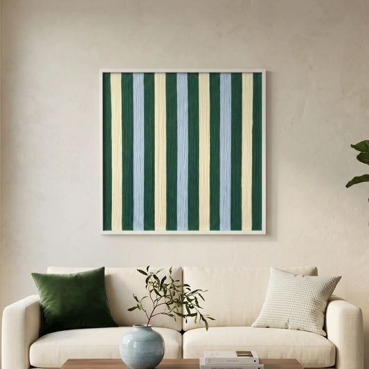 Square hand-woven wool wall art featuring vertical stripes in forest green, pale blue, and cream, hanging above a cream-colored sofa with green accent pillows.