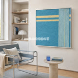 Infinite Serenity SQ020 framed blue yarn art beside a pale blue lounge chair in a calm reading corner