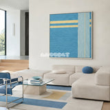 Infinite Serenity SQ020 blue and yellow framed yarn art above a white sectional sofa in a minimalist living room