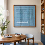 Blue Bridge Over the Pond SQ024 light blue framed yarn art above a round wood table in a sunlit dining room