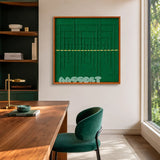 Green Shadow Weave SQ025 emerald green framed yarn art beside a wood desk in a sunlit home office