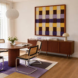 Mrs Dalloway SQ043 purple yellow cream and brown framed yarn art above a fluted wood sideboard beside cane chairs in a bright dining room