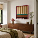 Coral Stripe Pup Wander SQ046 pink olive cream teal and brown framed yarn art with a dog motif above a wood dresser in a warm bedroom
