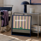 Cerulean Stripe Pup Frolic SQ047 blue lilac cream green and black framed yarn art leaning beside a chrome console in a Bauhaus style lounge