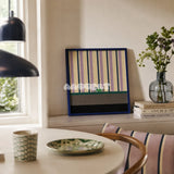 Cerulean Stripe Pup Frolic SQ047 striped framed yarn art with a dog motif displayed by a window beside a round table in a bright dining nook