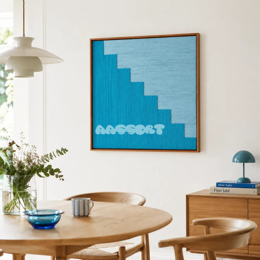Azure Sky Woven SQ048 Blue Sky hand-wrapped yarn wall art above a round wood table in a bright Scandinavian dining room
