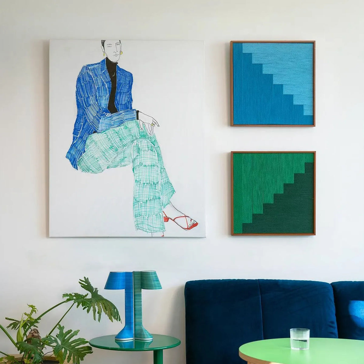 Azure Sky Woven Blue Sky and Green Forest fiber wall art variants displayed beside a fashion illustration in a colorful living room