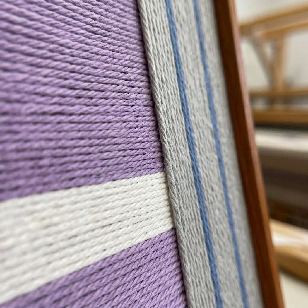 Close-up side view of Material Mass SQ084 framed textile art showing dense violet yarn and the sleek frame finish.