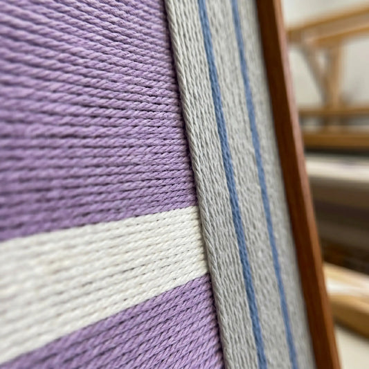 Close-up side view of Material Mass SQ084 framed textile art showing dense violet yarn and the sleek frame finish.