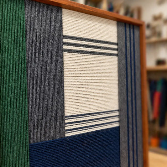 Angled view of Needle and Ink SQ085 framed textile art highlighting its hand-wrapped yarn texture and geometric structure.