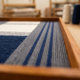 Macro view of Needle and Ink SQ085 showing precise navy yarn winding and dimensional structural layering.