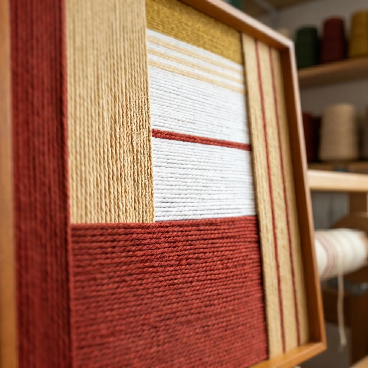 Angled close-up of Sun-Baked Terra SQ086 showing terracotta, ochre, and cream yarn in a textured geometric layout.