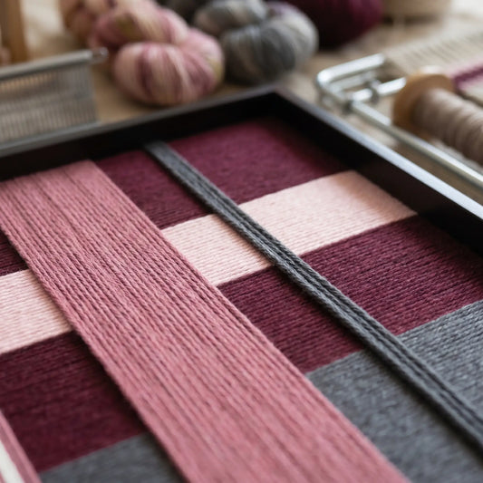 Macro view of Lilac Whispers SQ101 highlighting plum and pink hand-wrapped yarn texture in a black frame.