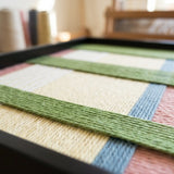 Low-angle studio view of Pastoral Lullaby SQ104 highlighting dimensional multi-directional yarn craftsmanship.