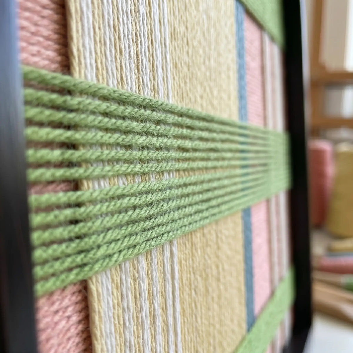 Macro view of Pastoral Lullaby SQ104 showing raised spring green yarn over pastel pink and yellow layers.