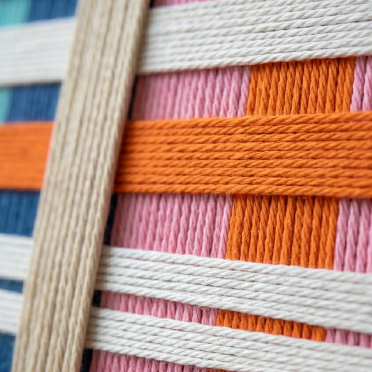 Close-up of Scale of Joy SQ109 showing handmade yarn texture and colorful interwoven geometric patterns.