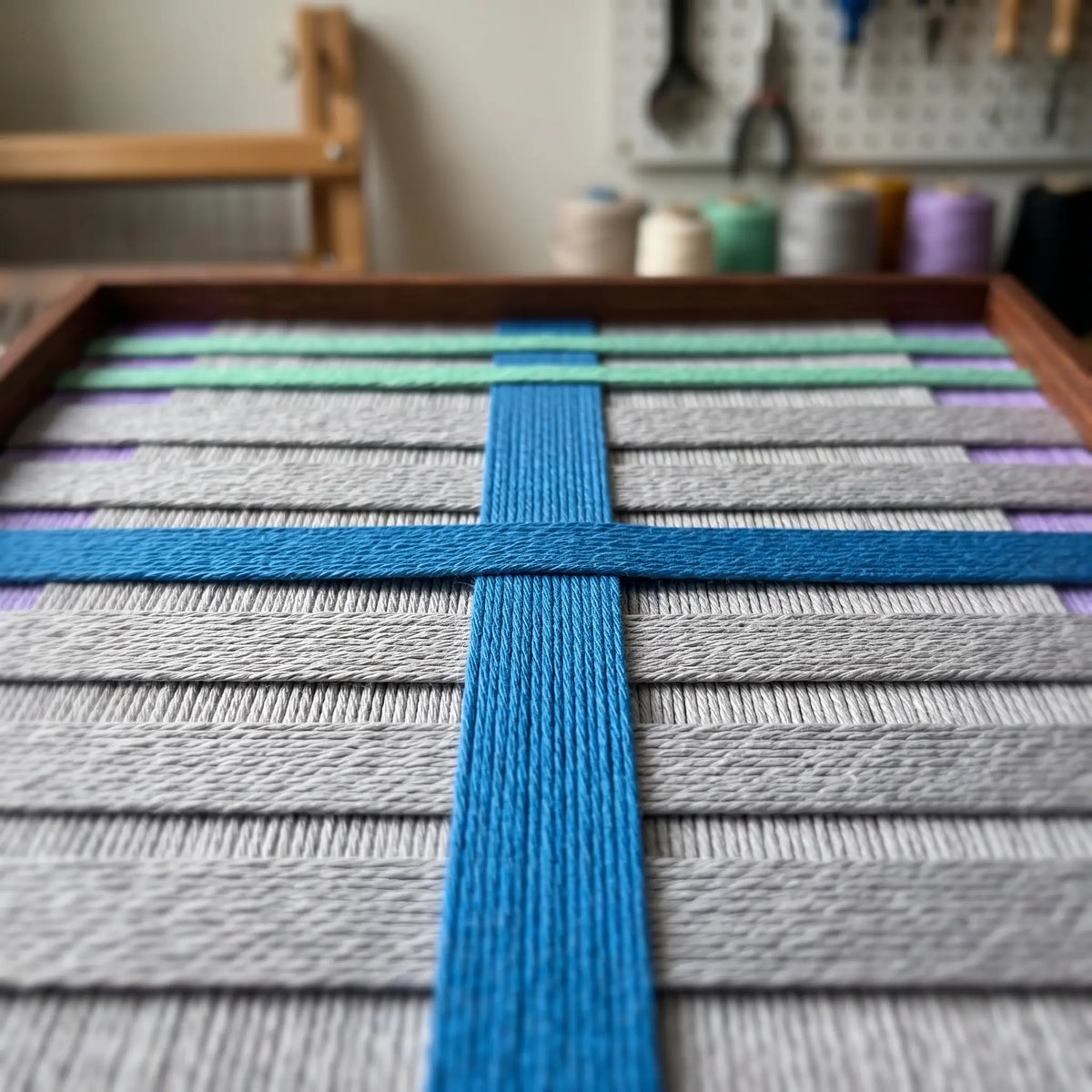 Workshop close-up of Cobalt Window SQ113 highlighting dimensional cobalt, mint, and gray yarn craftsmanship.