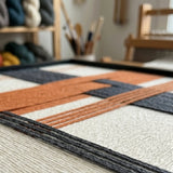 Macro workshop view of Terracotta Dusk SQ114 showing raised orange and charcoal yarn over a cream background.