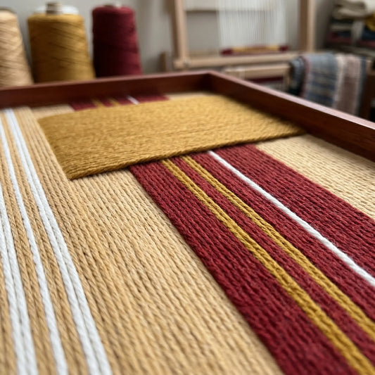 Angled close-up of Carmine Pulse SQ121 showing a raised mustard yellow yarn block over red, white, and beige stripes.