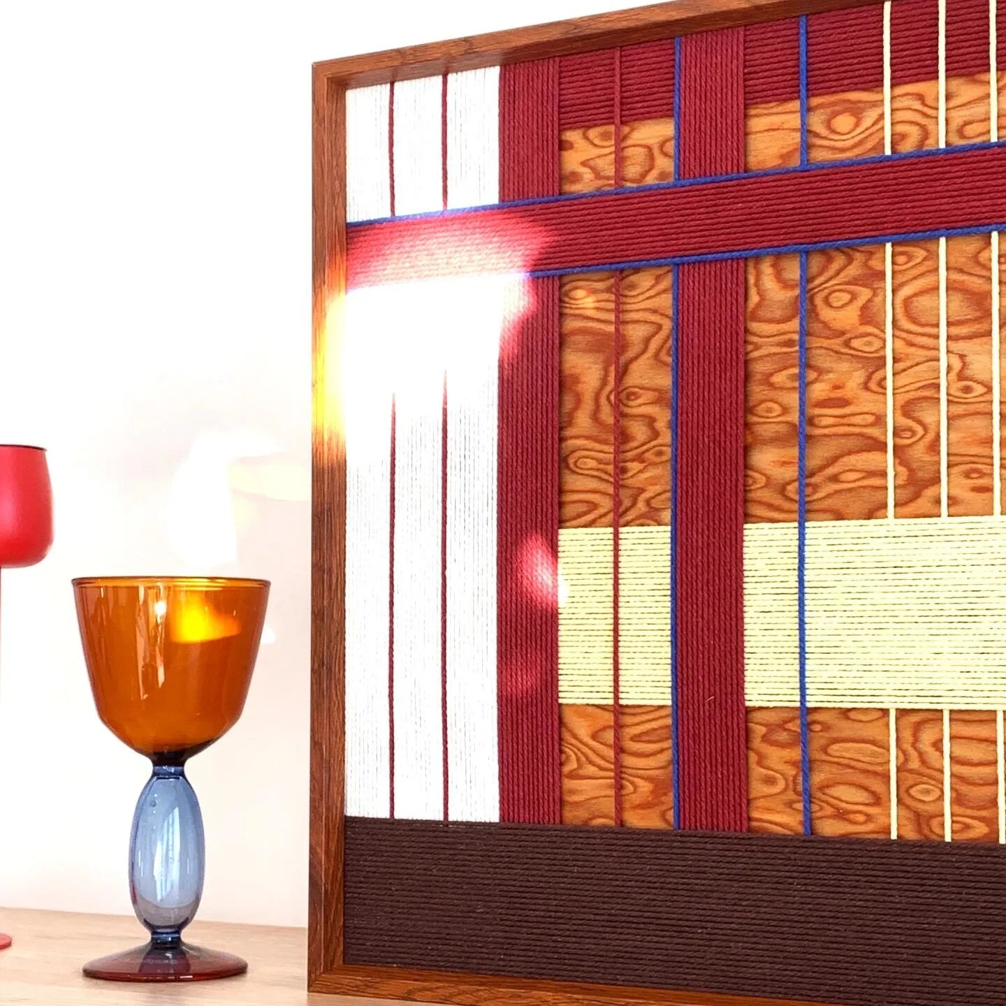 Close-up of a Festive Harmony SQ143 variation highlighting textured red and orange yarn with a soft light flare.