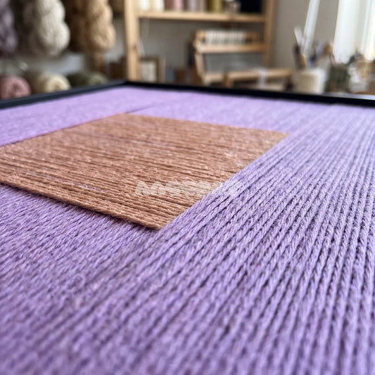 Plain Sight textile art detail: low-angle view of the raised peach-colored square on lavender fibers.