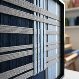 Angled close-up of the Starry Latitude framed wall art highlighting the dimensional navy and cream woven wool yarn patterns.
