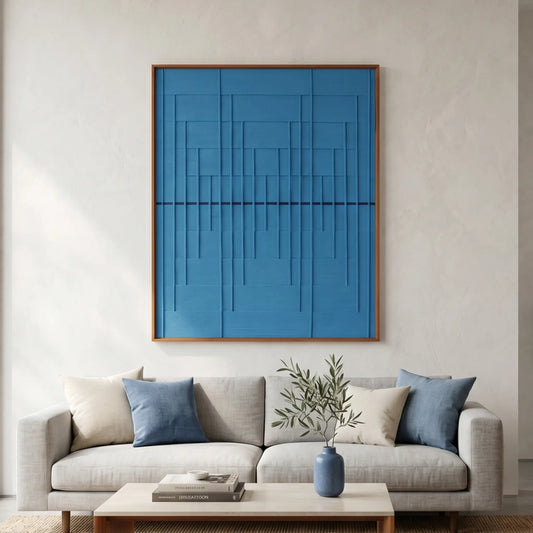 Large-scale blue textured fiber wall art hanging above a wooden sideboard in a bright, airy living room with a beige rug.