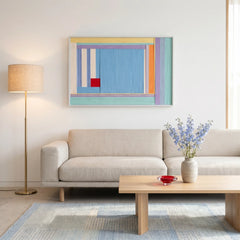 Vibrant blue and orange textured wool wall decor placed in a bright living area featuring a beige sofa and floor lamp.