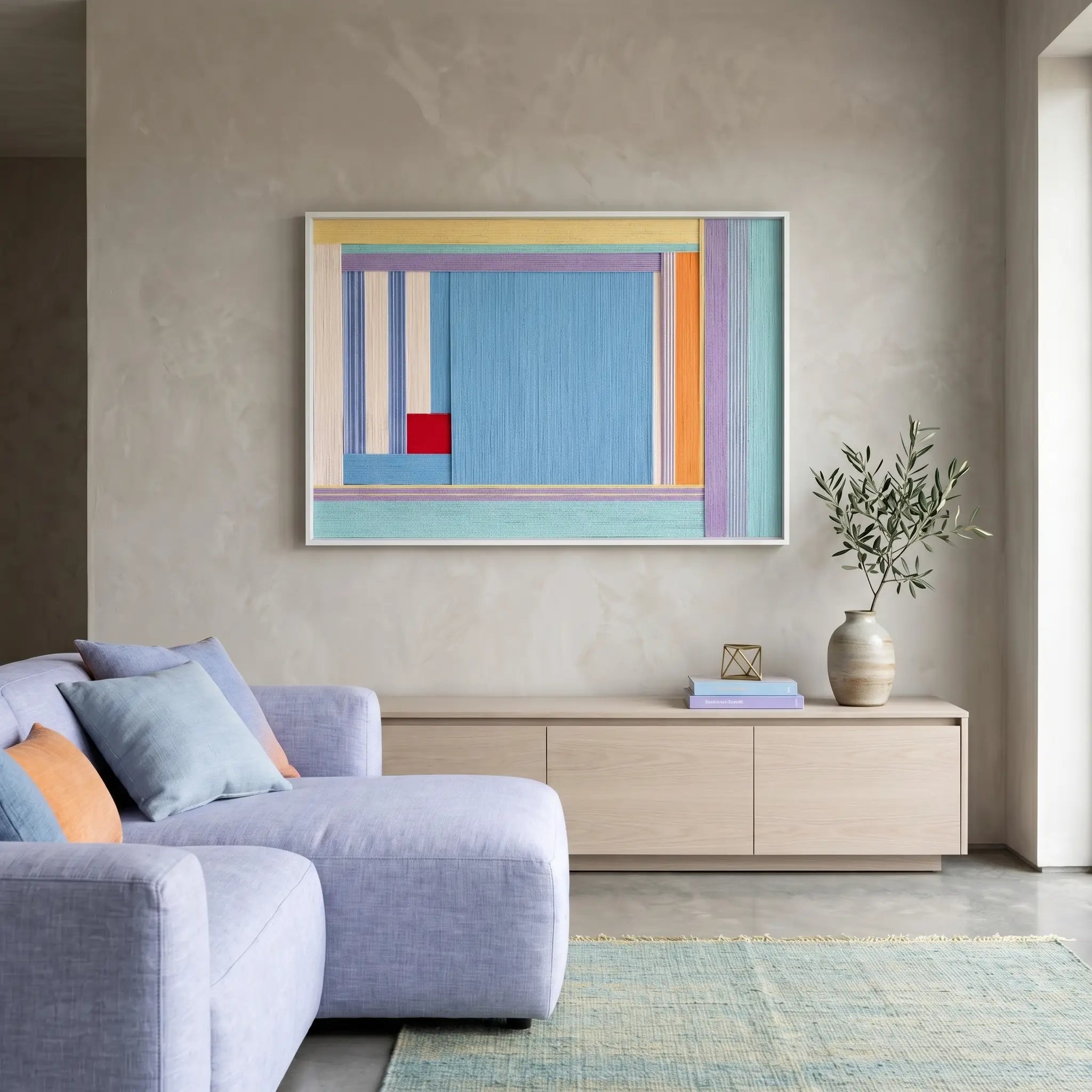 Handmade wool wall art piece hanging above a minimalist wooden credenza in a sophisticated living room with neutral concrete walls.