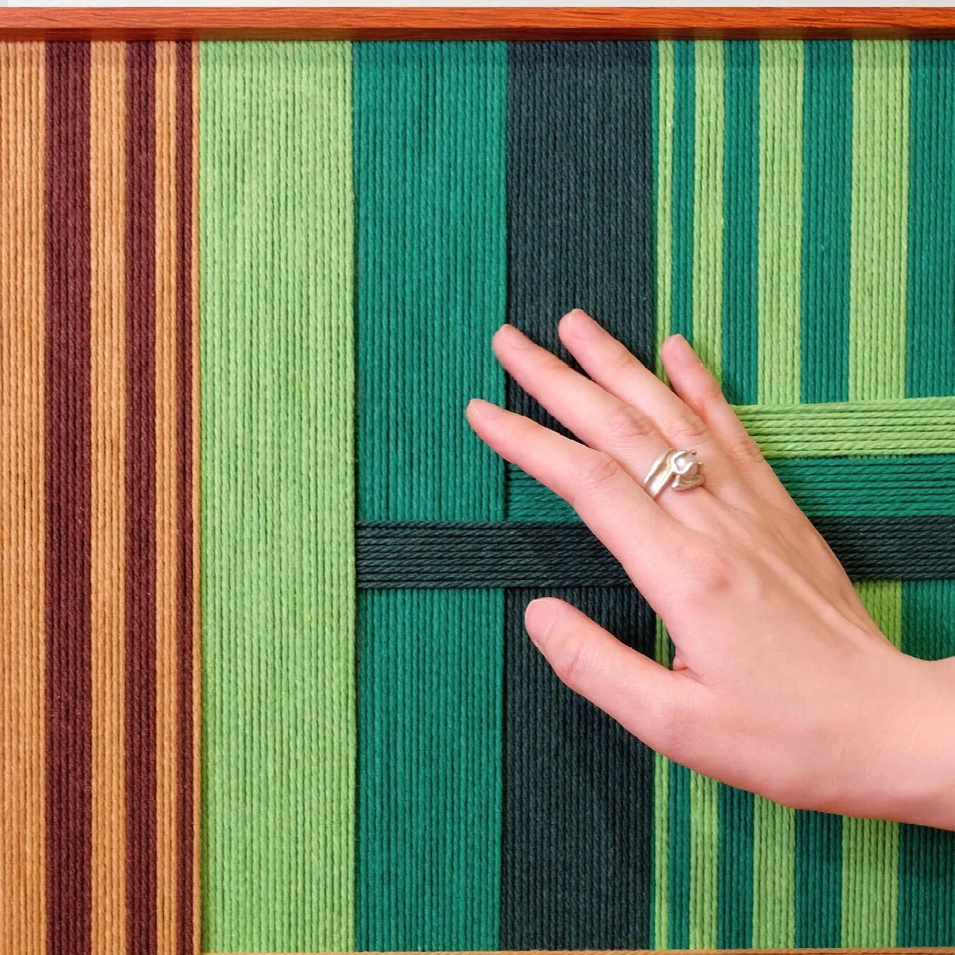 Close-up of Summer Mountain Walk yarn wall art revealing tight looped wool texture and crisp transitions between green and brown stripe panels.
