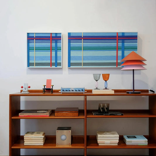Summer Story yarn wall art displayed on a wooden shelf next to books and ceramics, showcasing the clean stripe pattern and sturdy frame
